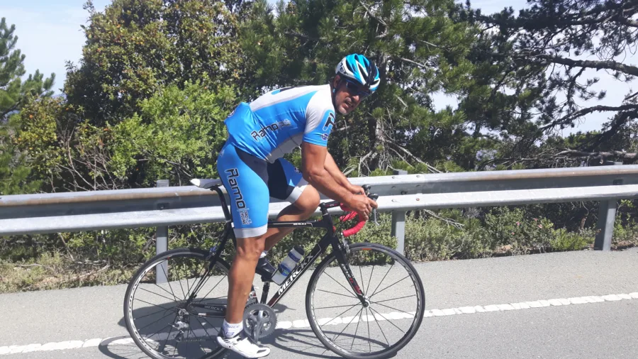 A rider in Ramo kit riding beside a crash barrier under pines