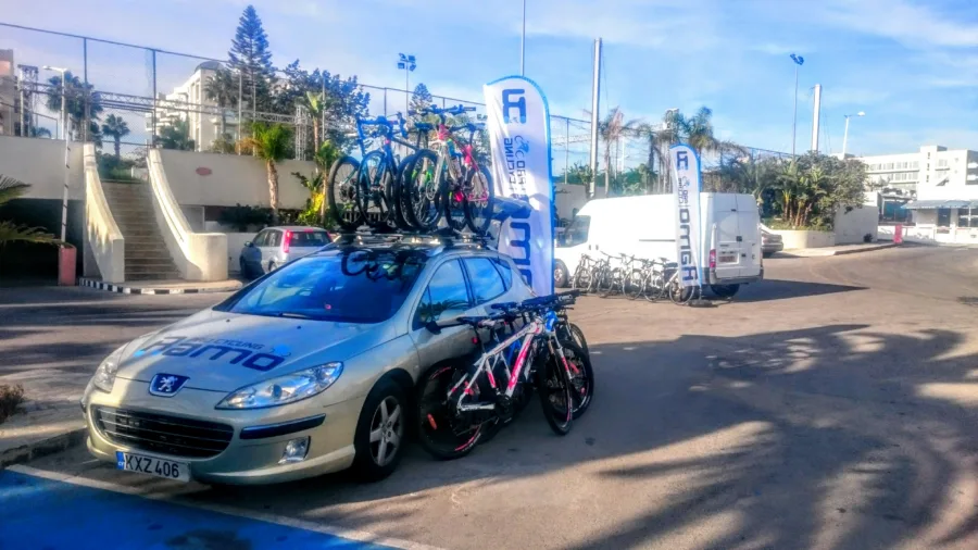 The Ramo team car with bikes on the roof beside a sports track