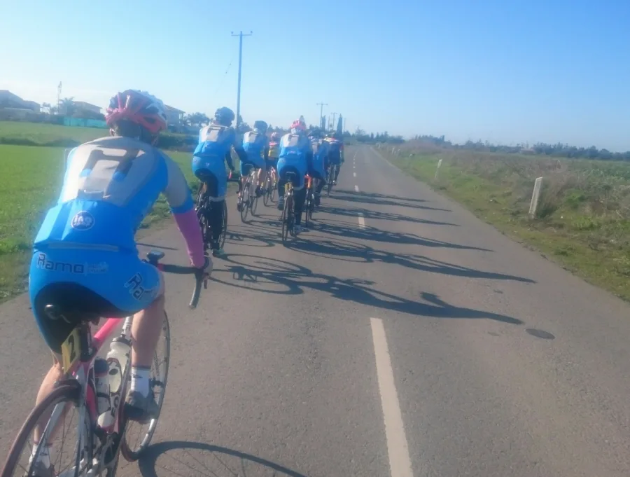 A group of riders strung out along a road, seen from the back of the group