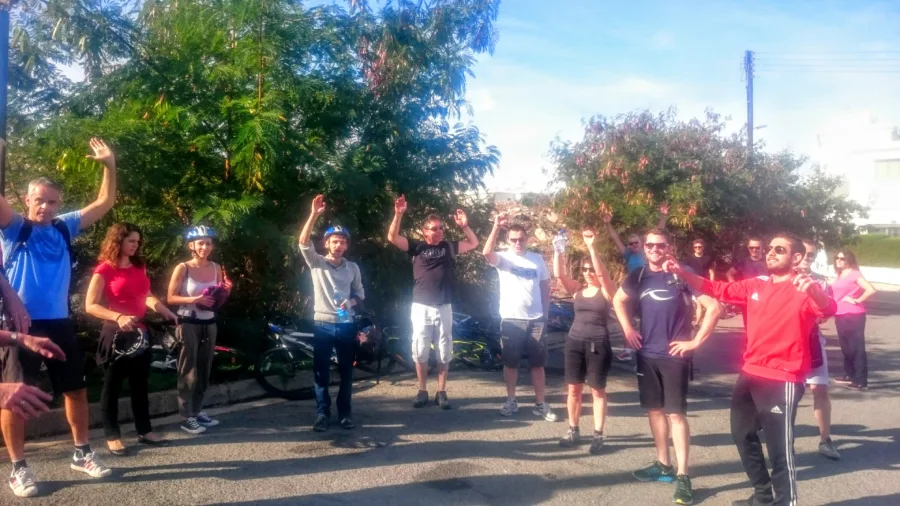 A group of riders and walkers with their arms raised beside a road