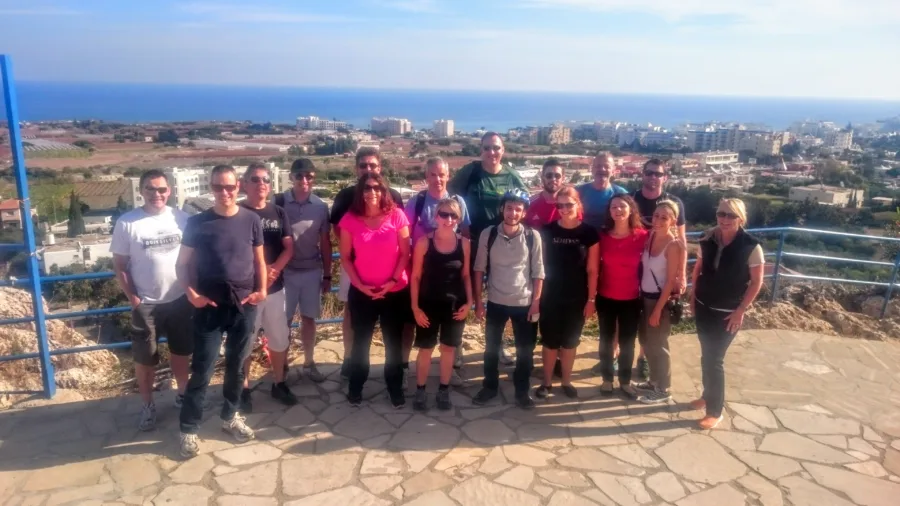 A large group standing along a wall on a viewpoint above a town