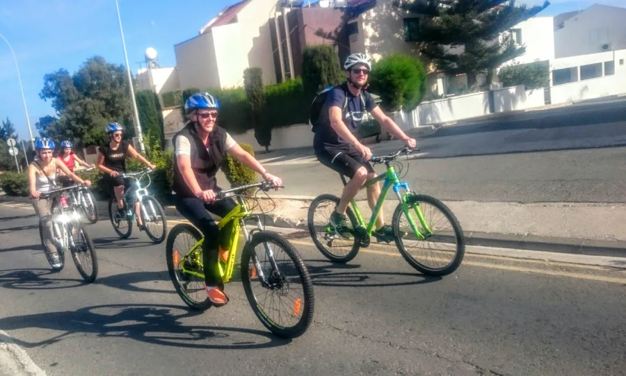 Riders on mountain bikes riding along a street beside a kerb