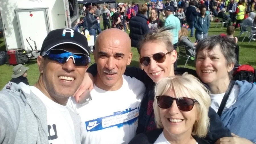 A selfie of five people at a race, crowds behind