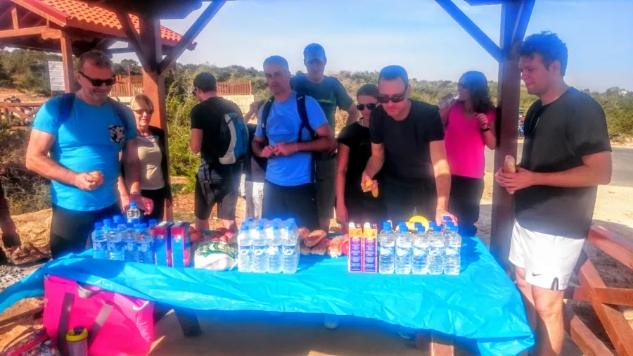 A table of water bottles and drinks laid out for riders under a shelter