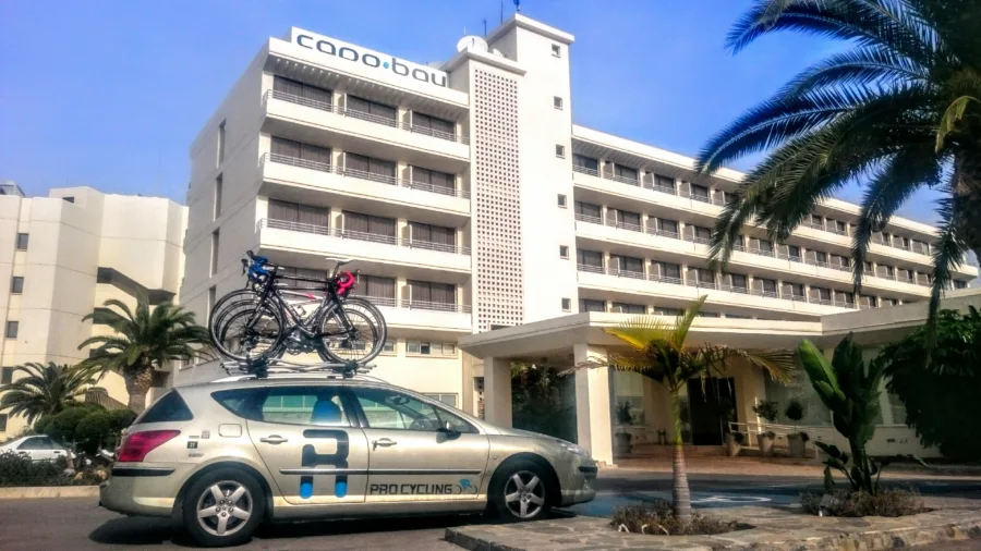 The team car with bikes on the roof parked outside a hotel