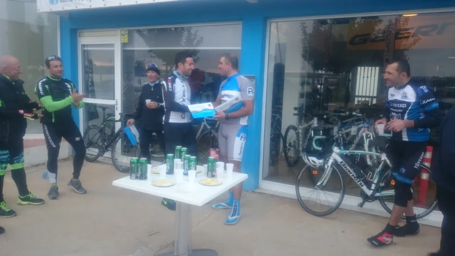 Riders standing with drinks at a table outside the shop