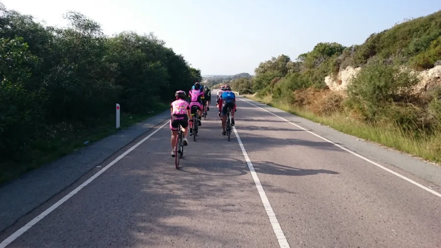 Riders on a road running between green banks