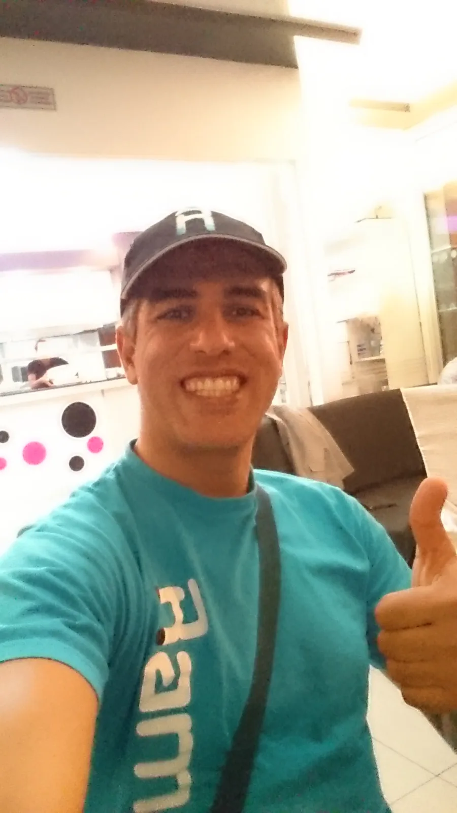 A man in a Ramo shirt giving a thumbs up indoors