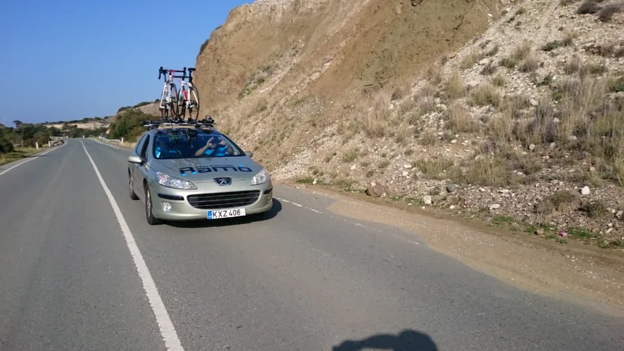 The team car coming down a road below a rock face
