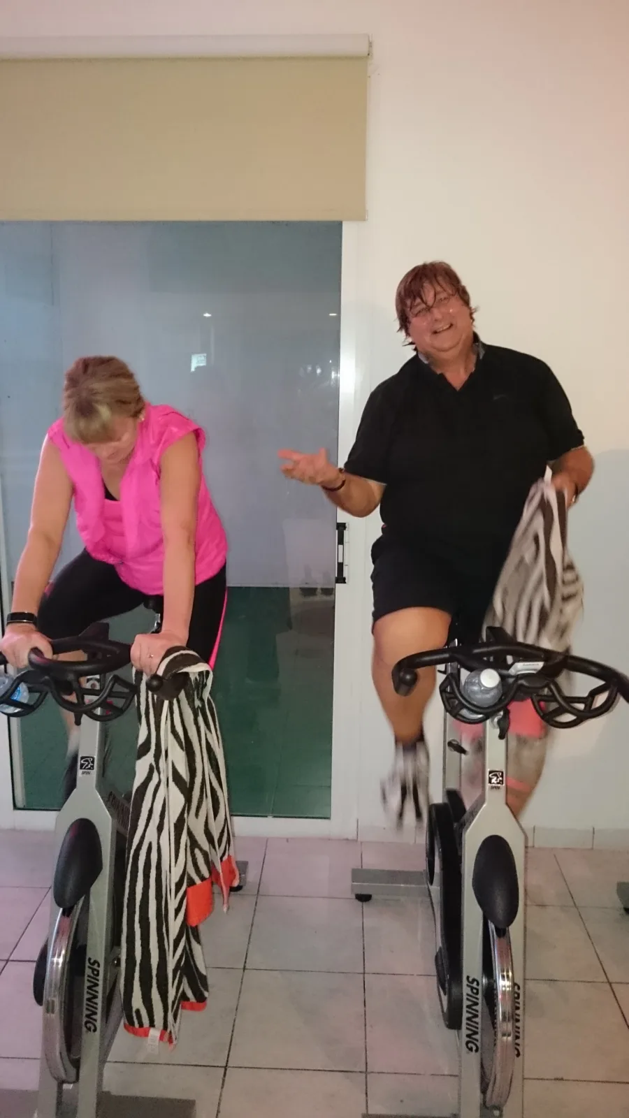 Two people riding stationary bikes indoors