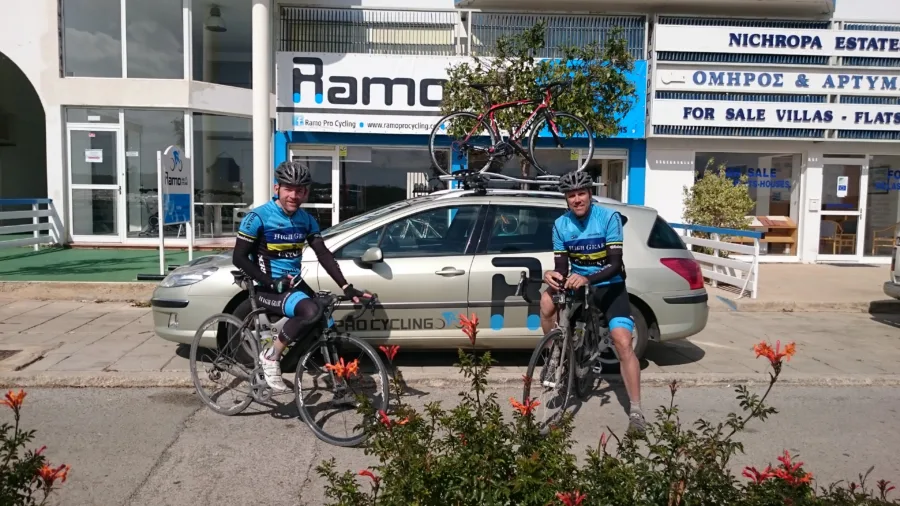 Two riders with their bikes outside the shop beside the team car