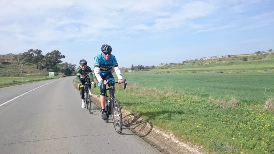 Two riders on a road running between green fields