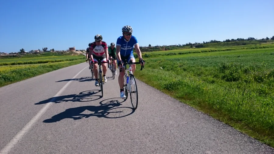 A group of riders riding towards the camera on a road through farmland