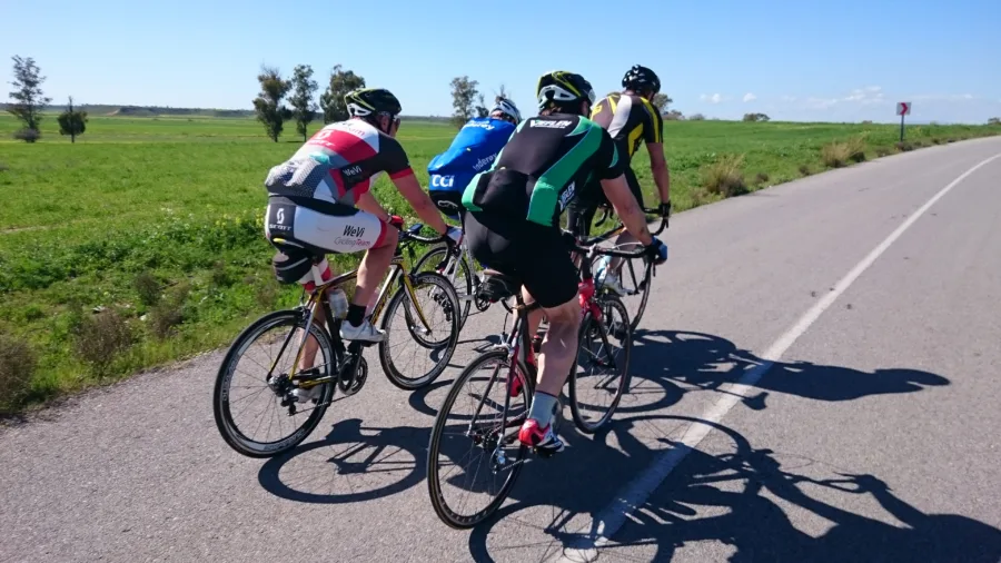 Three riders in team kit racing side by side on an open road