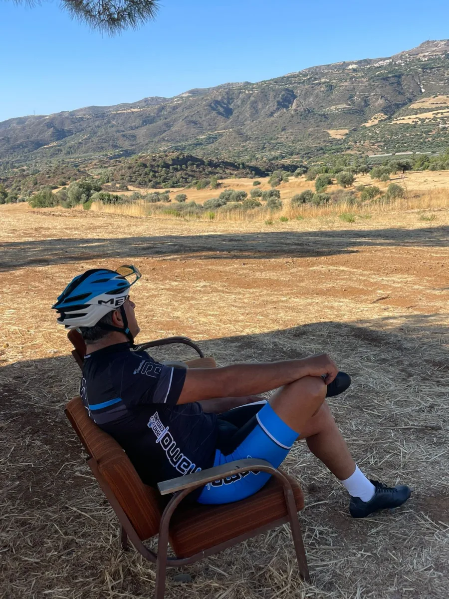 A rider sitting in an armchair left in a dry field beside the road