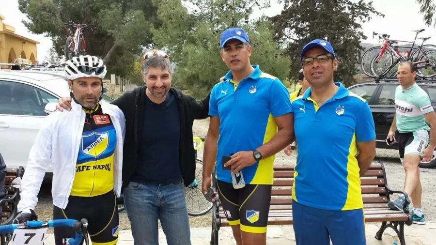 Four men standing beside a car with bikes on a bench behind
