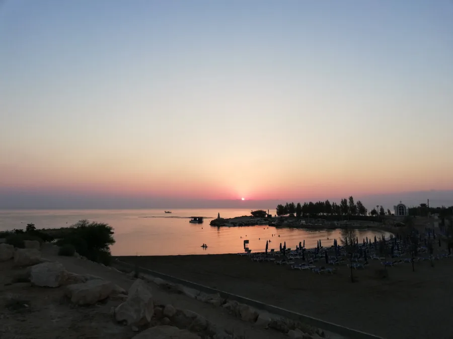 The sun rising over a bay with sunbeds along the shore