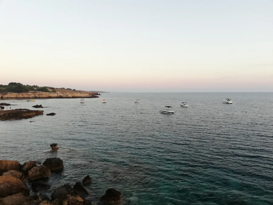 Boats moored in clear water off a rocky shore