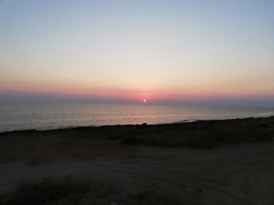 The sun rising over the sea seen from a dirt track