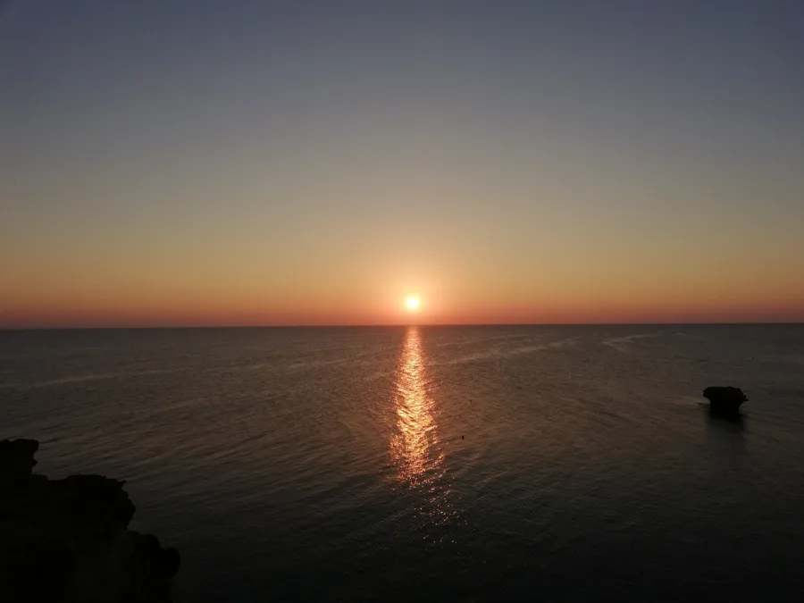 The sun setting into the sea off a rocky Cyprus shoreline