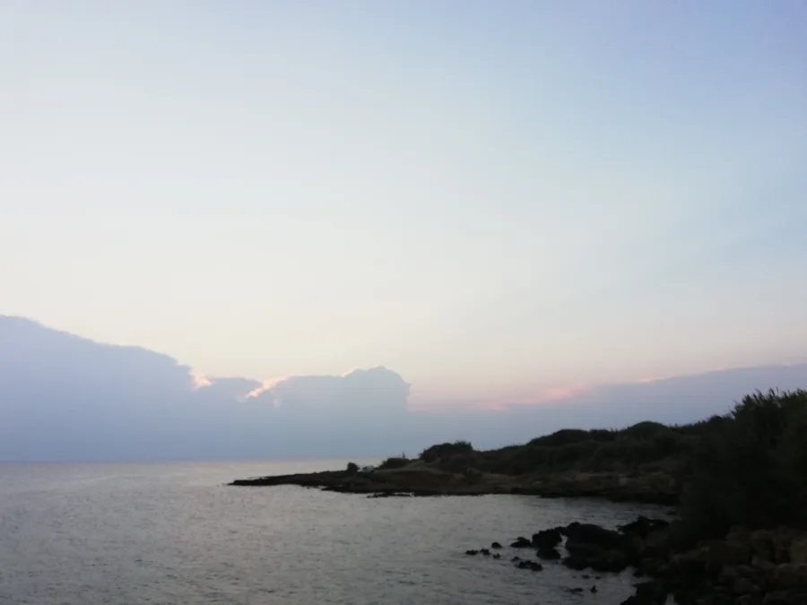 A rocky headland and calm sea under a soft early-morning sky