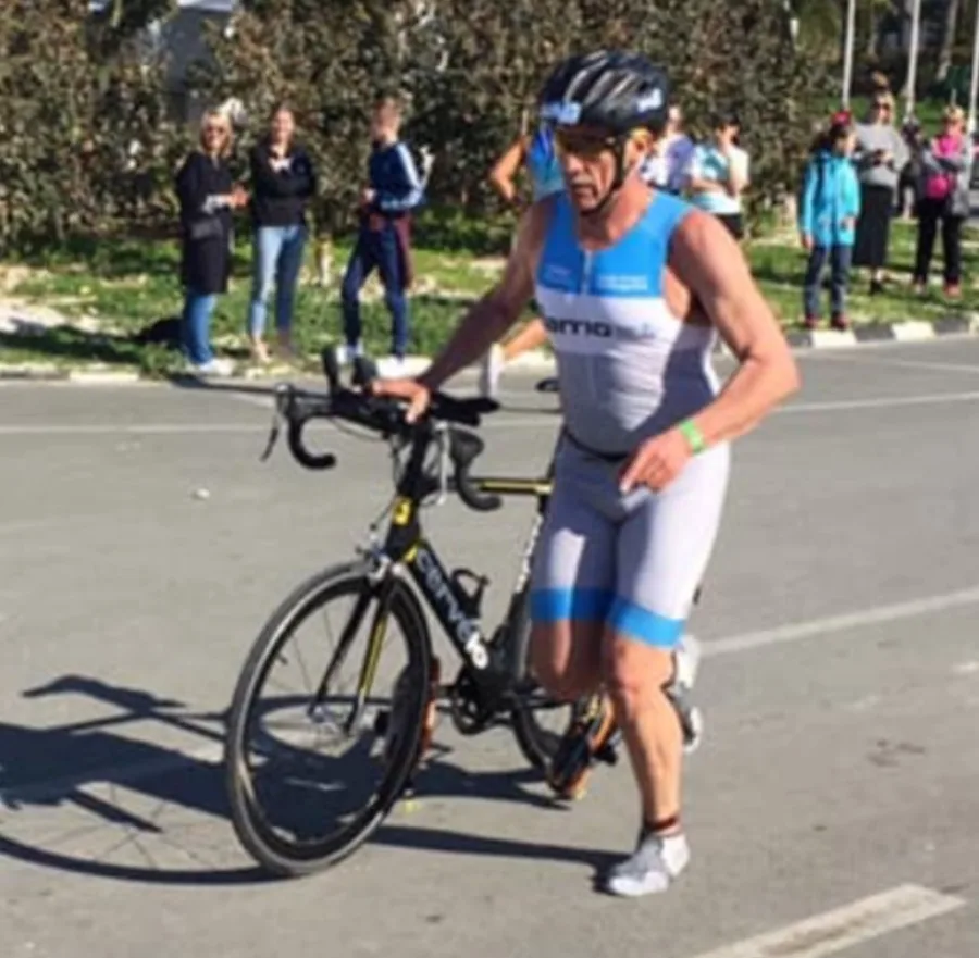 A triathlete pushing a time-trial bike towards transition