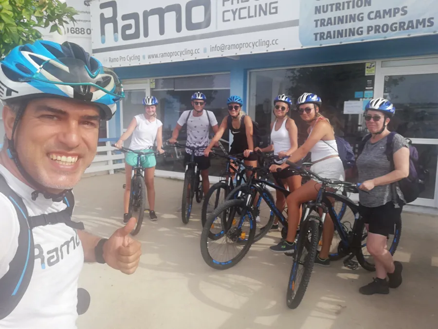 A group with mountain bikes gathered on the pavement outside the Ramo shop