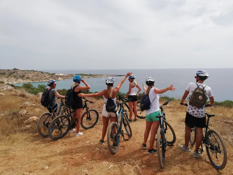A group with mountain bikes standing on a rocky headland above the sea