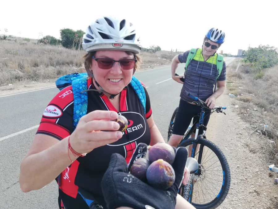 Two riders with mountain bikes, one holding figs picked at the roadside