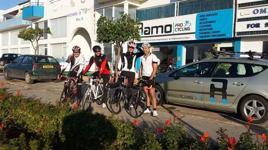 A group of riders with their bikes outside the Ramo shop beside the team car