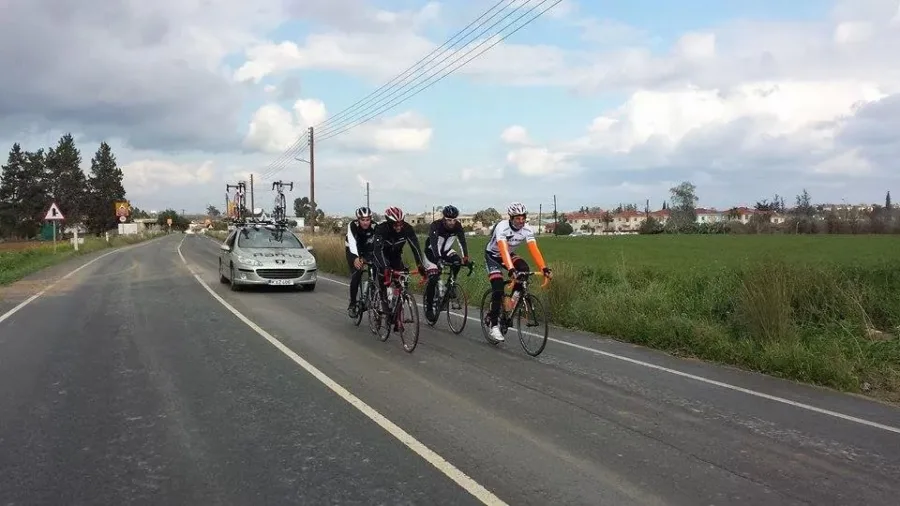 Riders on a road with the team car following behind