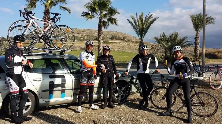 Riders and the team car stopped beside a row of palms