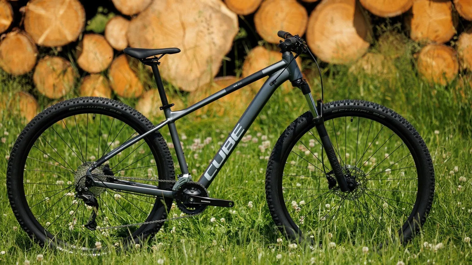 Cube Aim SLX rower górski typu hardtail na trawie przed ułożonymi pniami